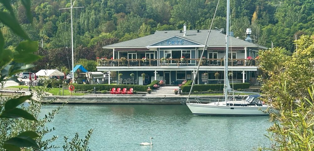 The CBYC clubhouse seen across the water, with a sailboat at the dock
