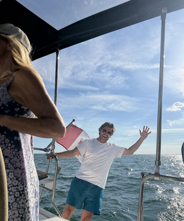 A member waving from the bow of a boat on the lake