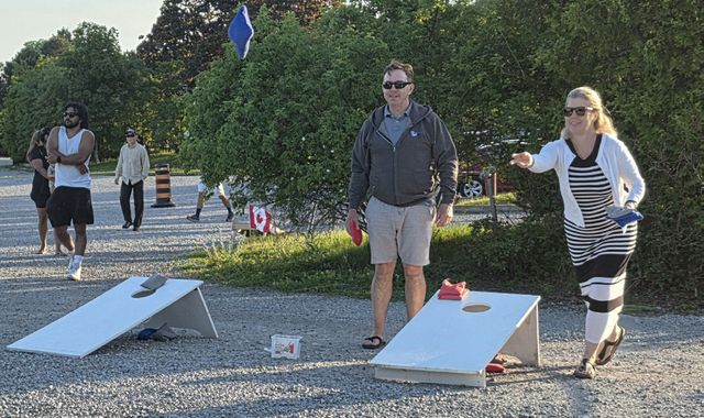 Members playing cornhole on the lawn