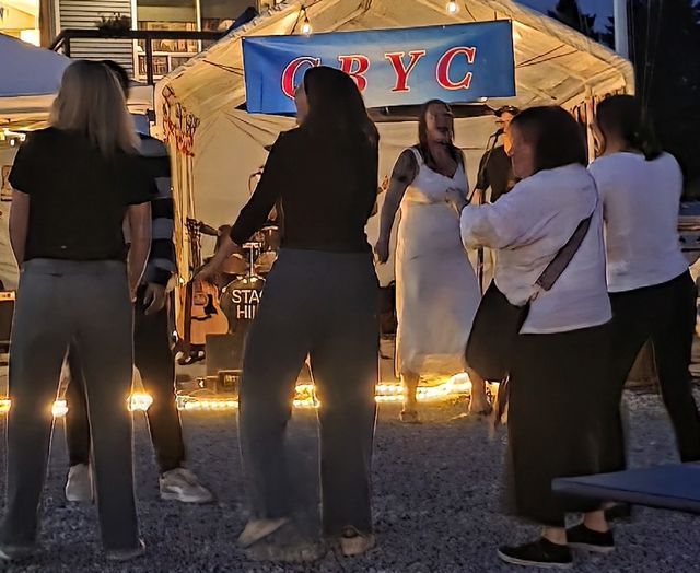 Members dancing outdoors at an evening event under the CBYC banner