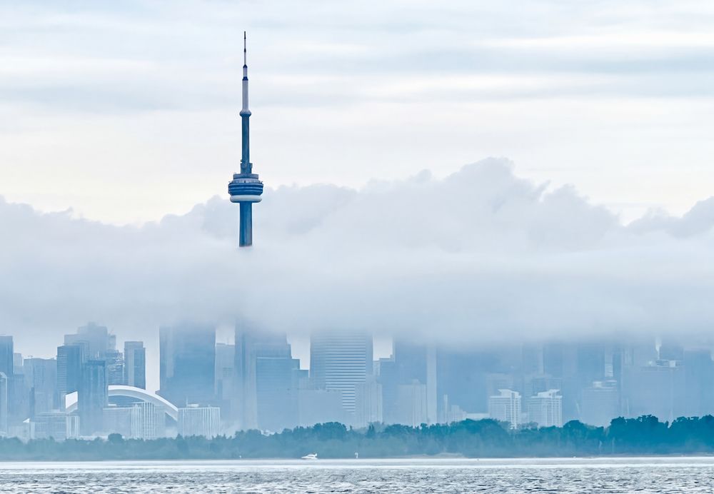 The CN Tower rising above low fog over the Toronto skyline