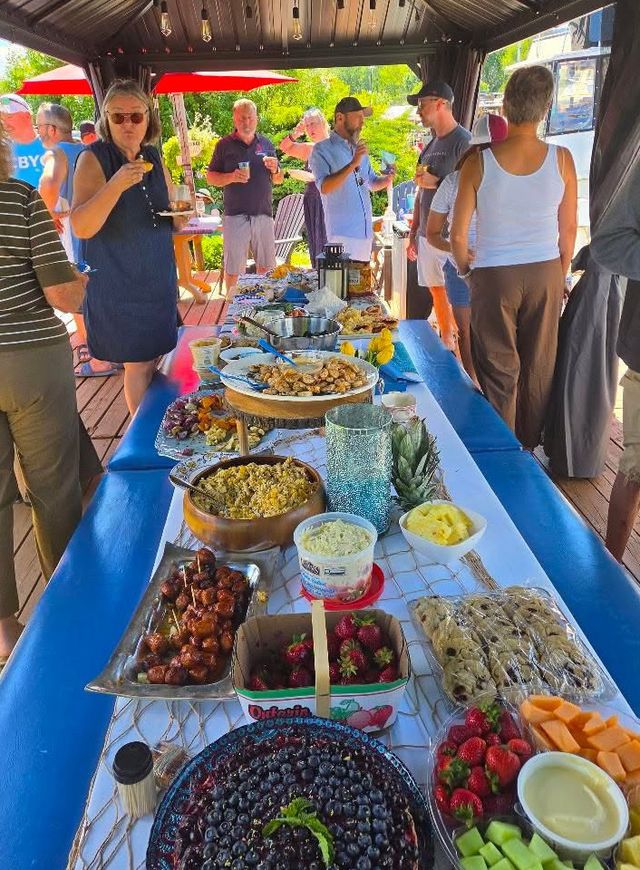 A long buffet table on the dock at a Sips & Slips gathering