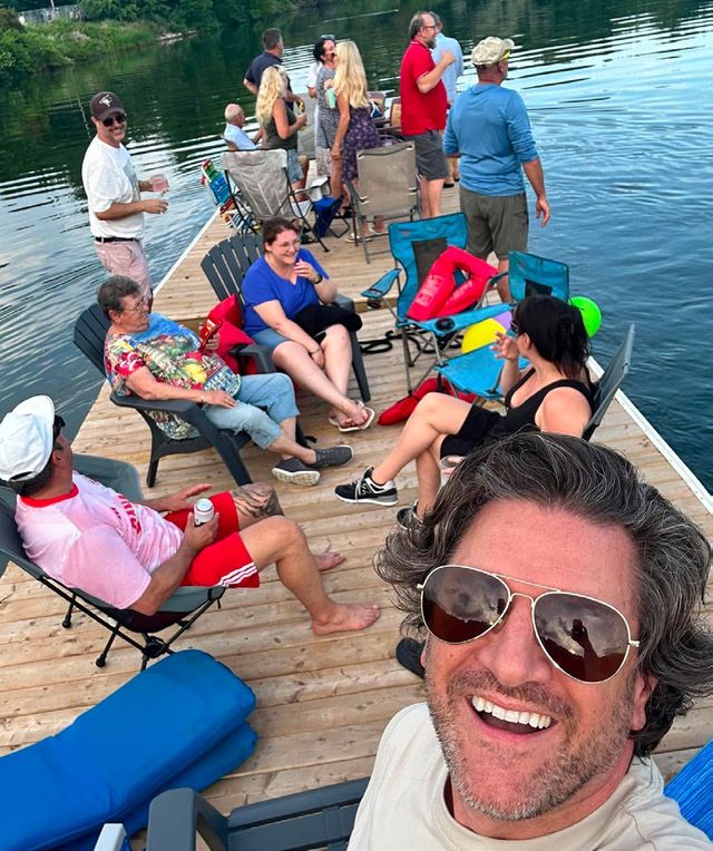 Members relaxing on a dock, with a smiling man in sunglasses in the foreground
