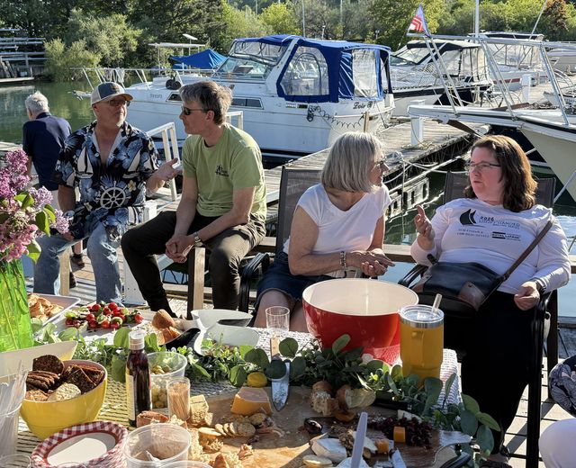 Members sharing food and drinks at a dockside table